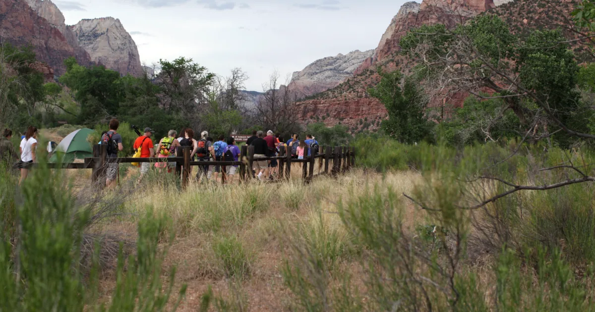 Visitors crowd a national park overlook while staff manage heavy summer use and worn infrastructure